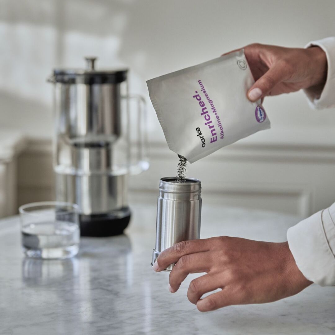 personne versant les granulés filtrants aarke enriched dans la carafe filtrante aarke purifier